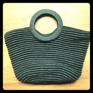 Black woven straw handbag with circle handle.